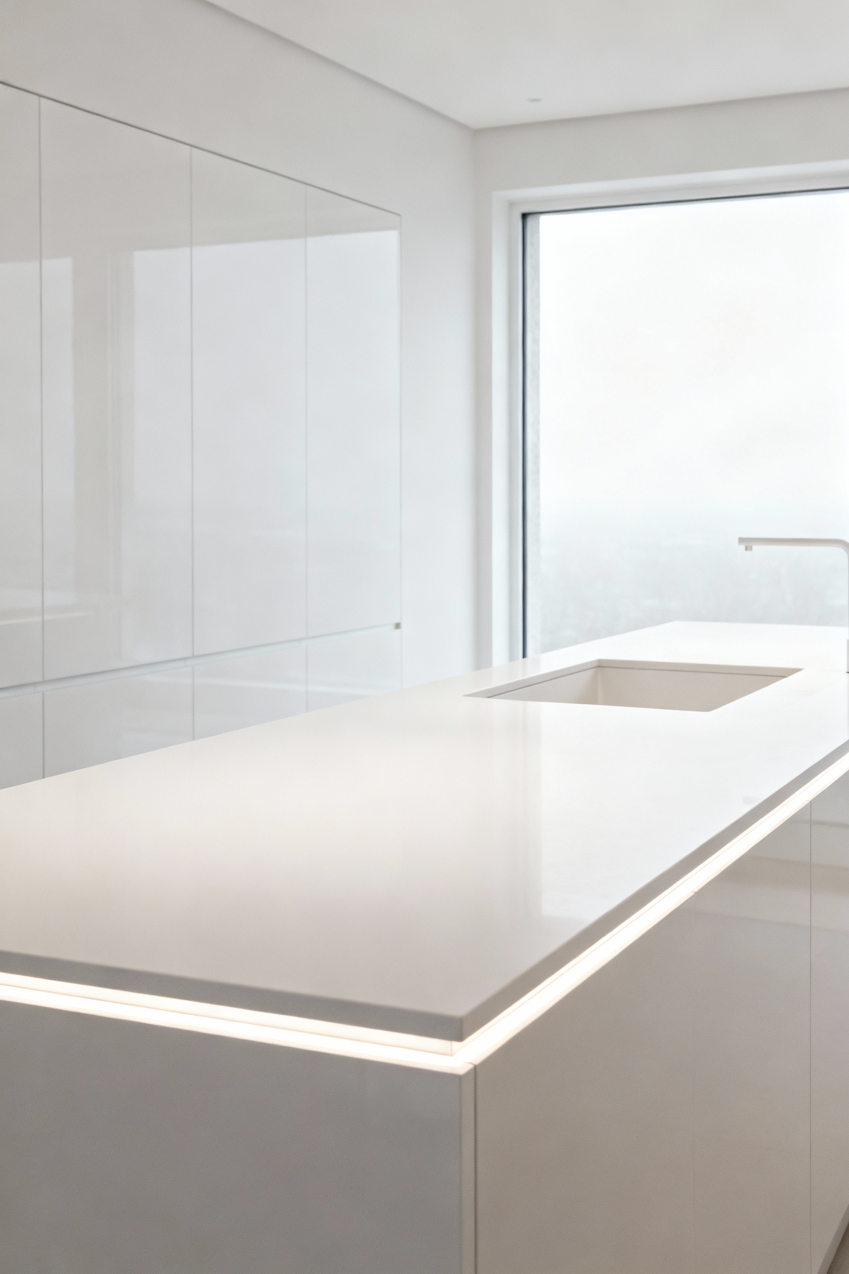 Modern kitchen island with seamlessly integrated white solid surface recessed sink, highlighting an uninterrupted counterscape.