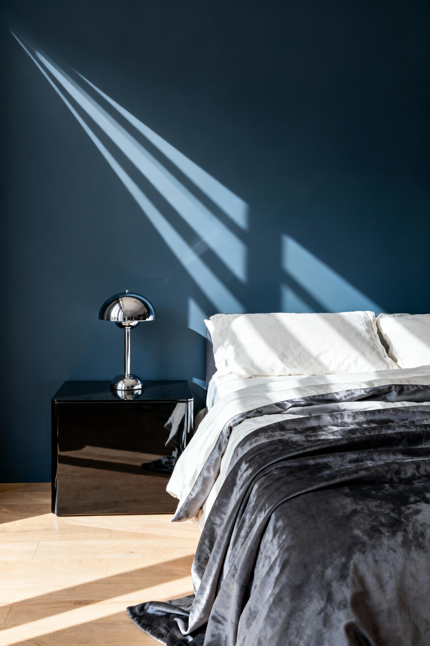 Small bedroom inspiration demonstrating textural contrast using matte slate blue walls and high-gloss black lacquered furniture to create visual movement and depth.