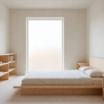 A small airy bedroom featuring light-toned ash wood furniture and bright natural sunlight reflecting off the walls.
