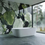 A modern bathroom design showcasing deep green Kolmården marble walls and silk-brushed Norwegian Oppdal slate flooring under soft natural light.